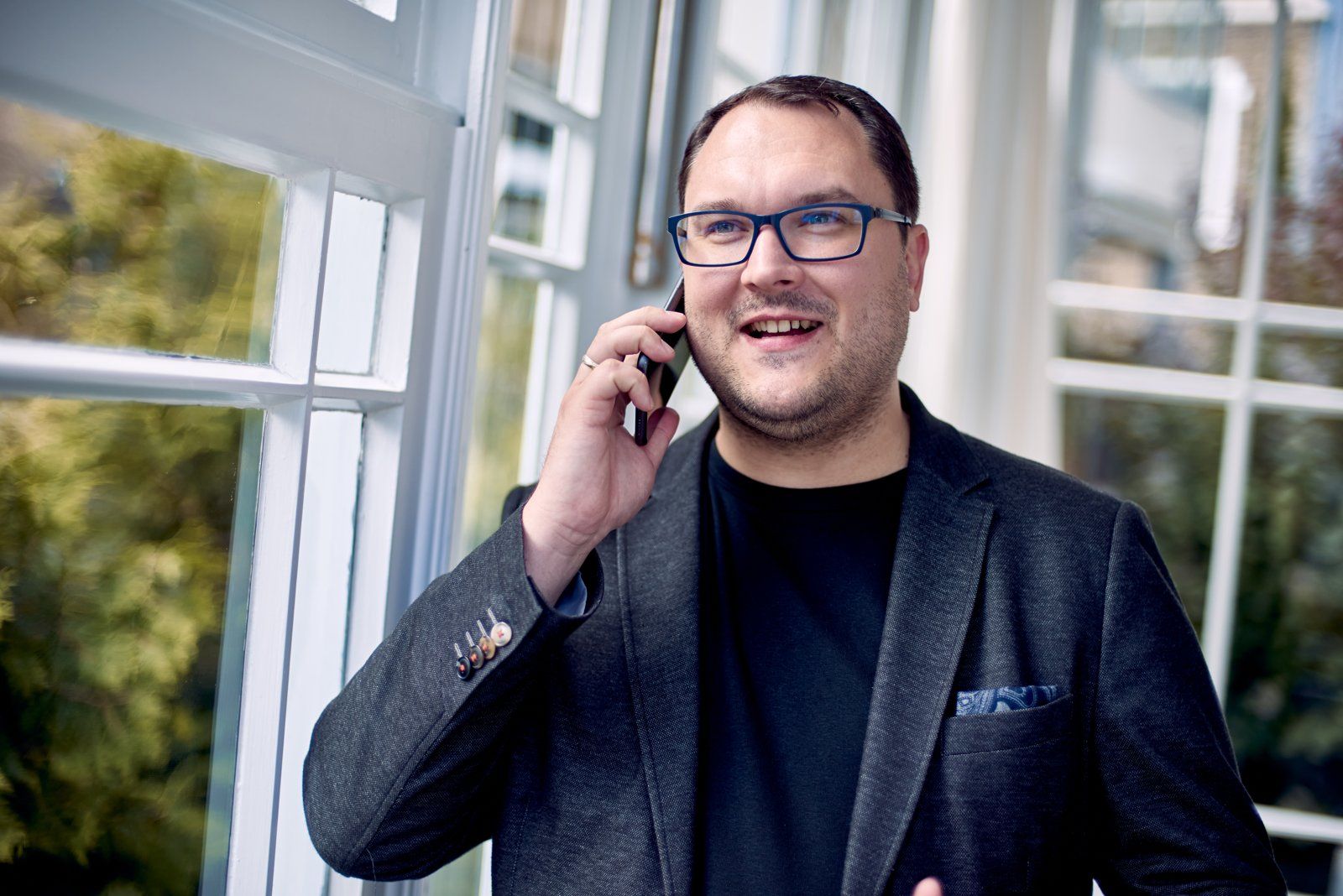 Thomas Schacht telefoniert lächelnd am Fenster